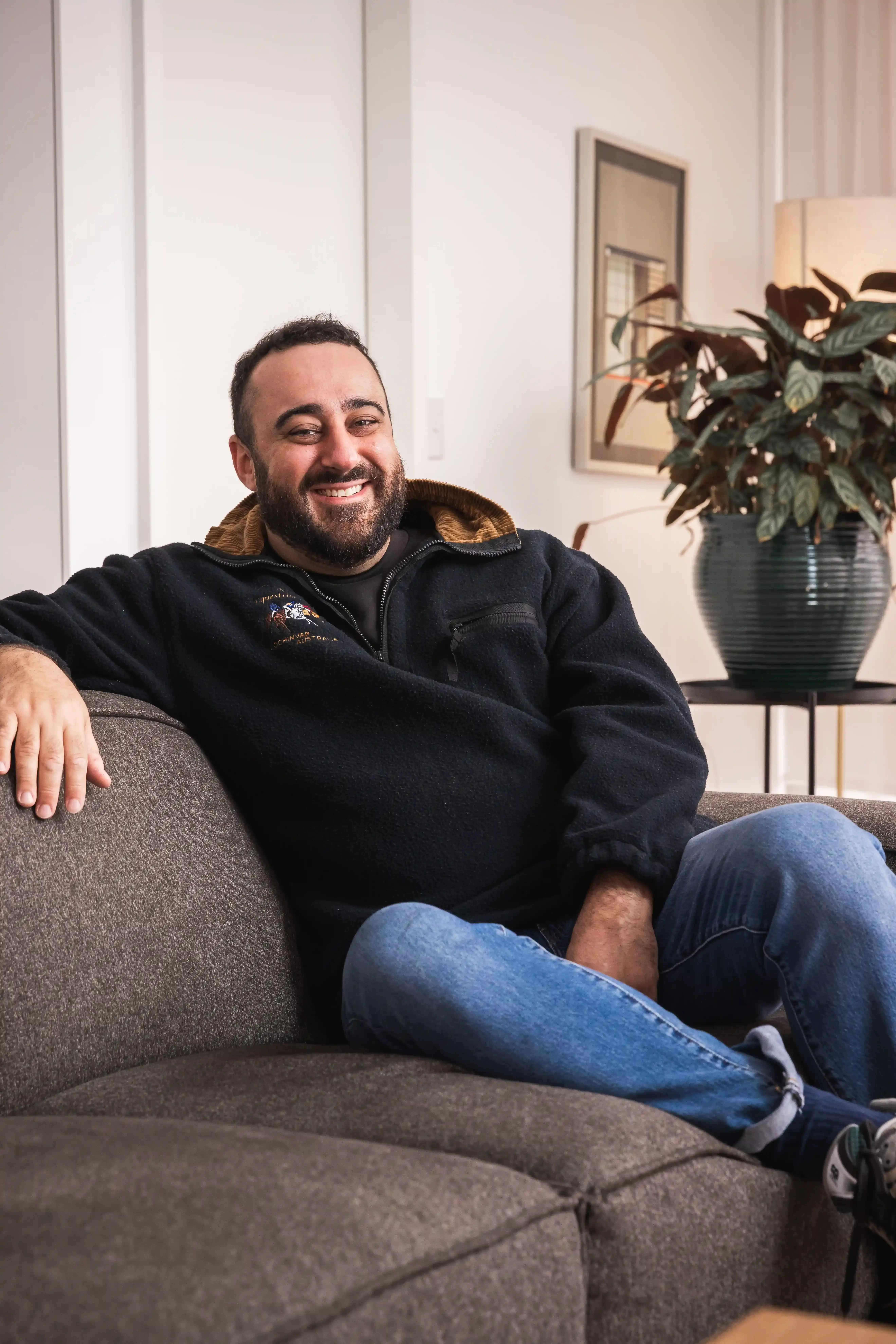 Sam Halcrow sitting on a couch, smiling